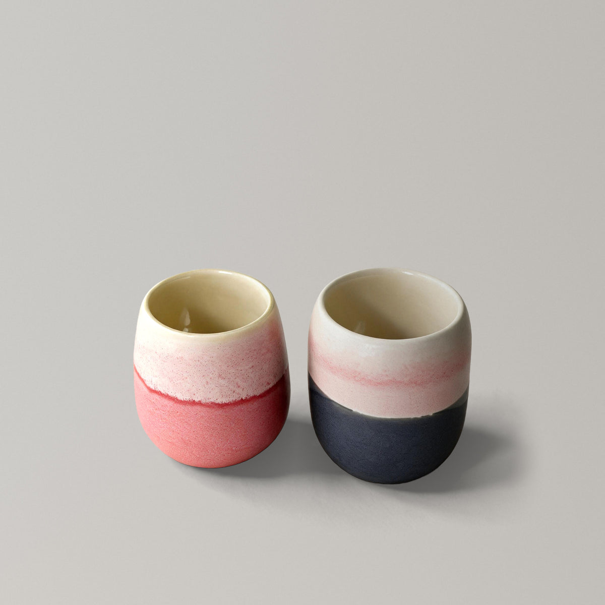 The Daily Duo, two handmade stoneware cups in coral and charcoal grey with speckled pink glaze